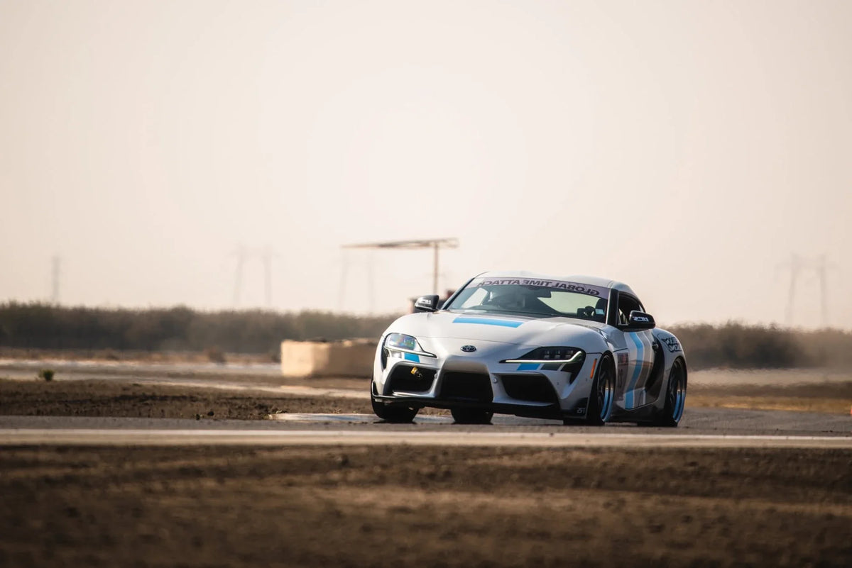 Toyota GR Supra race car in Megan Racing livery cornering on a track